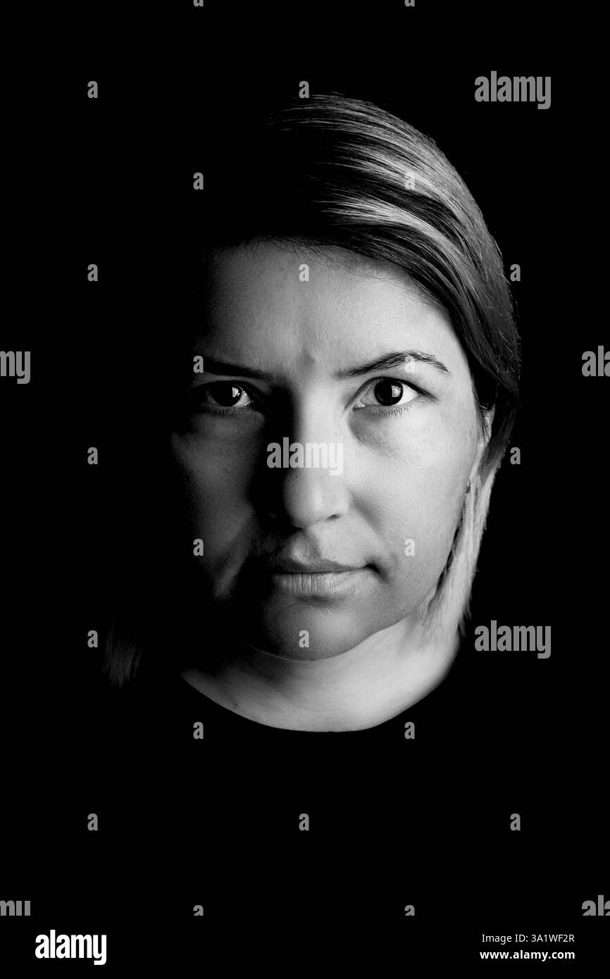 Ritratto in studio di una donna di 40 anni su sfondo nero. Foto Stock