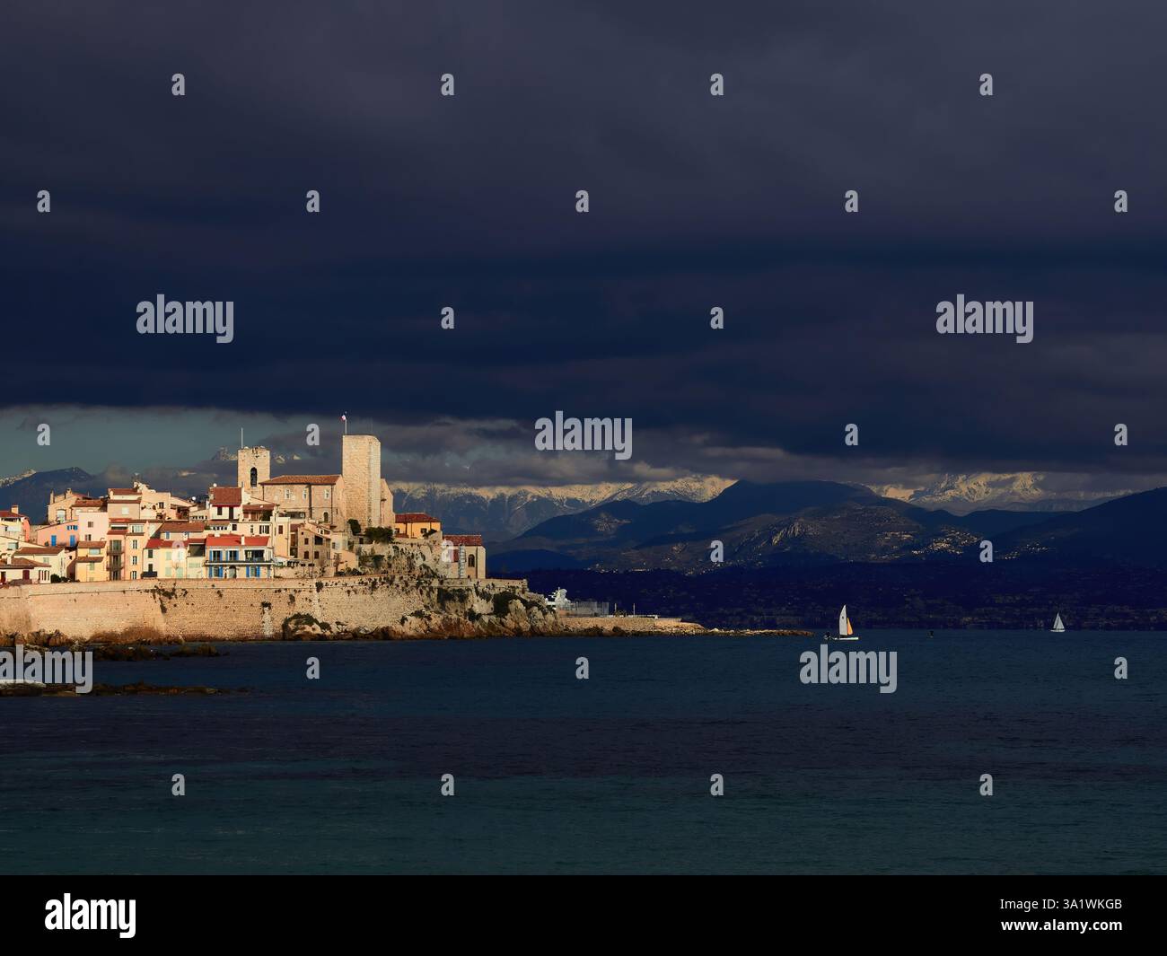 La maestosa città costiera di Antibes sotto i cieli nuvolosi e lo sfondo delle montagne Foto Stock