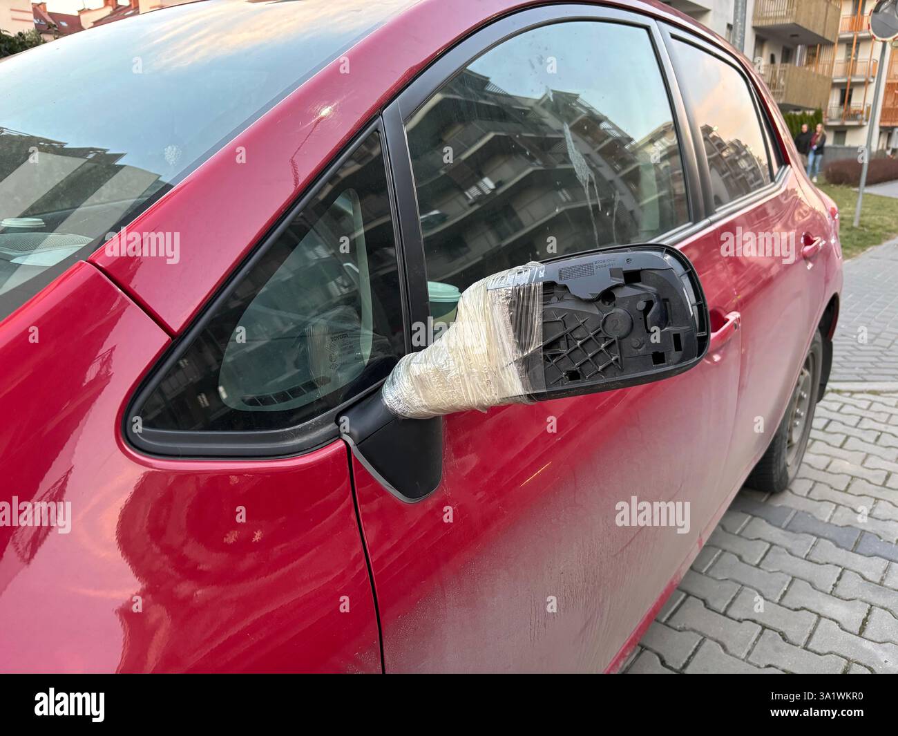 un'auto rossa con specchietto laterale danneggiato o rotto, riparata o riparata con nastro adesivo in città Foto Stock