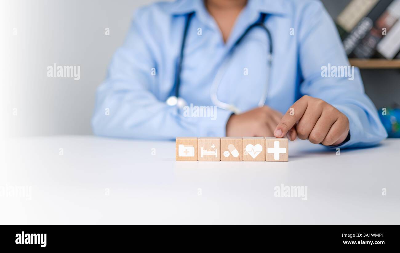 Concetto di assicurazione sanitaria, salute e accesso al concetto di salute benessere, mano del medico che tiene impilato in legno con le icone mediche e ospedaliere dell'assistenza sanitaria Foto Stock