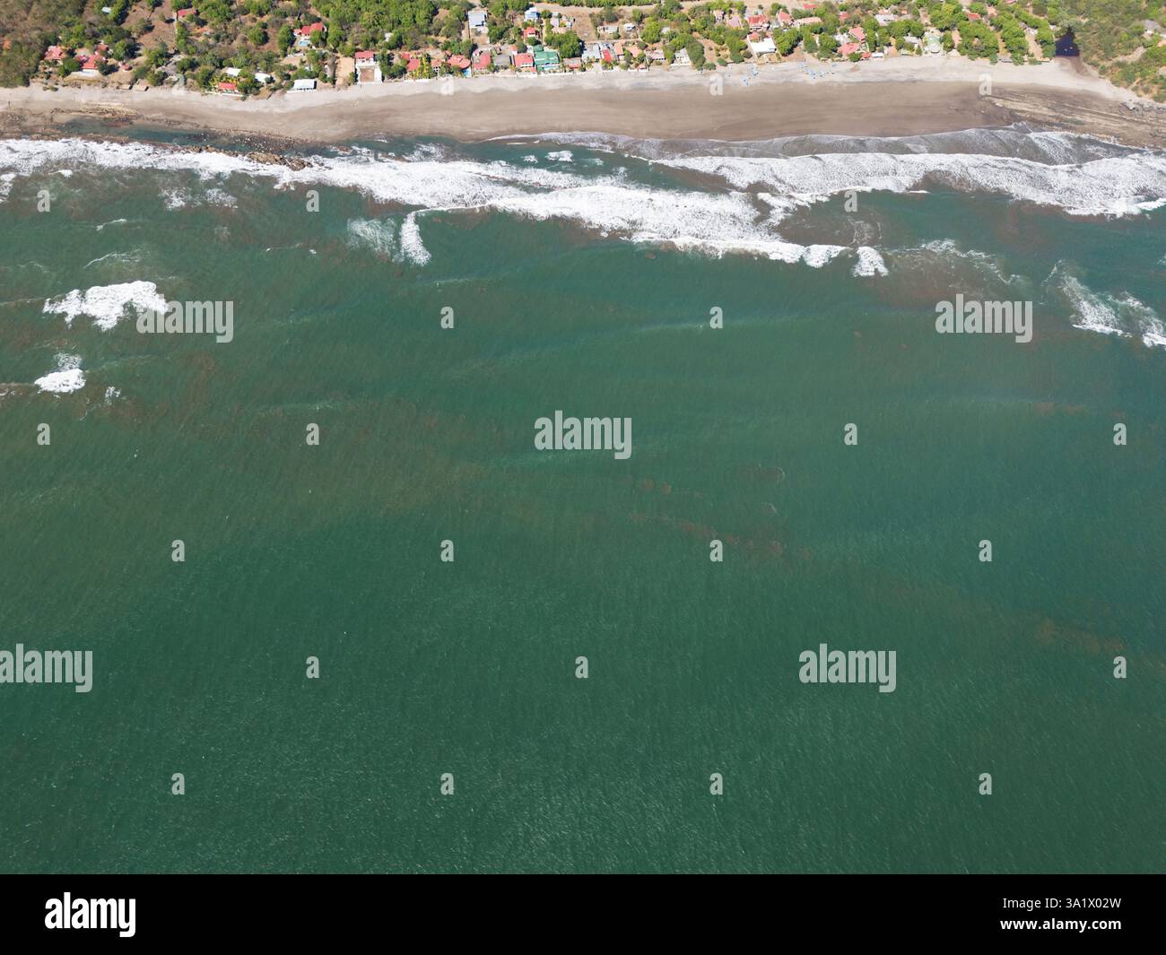 La pittoresca vista della spiaggia tropicale mostra dolci onde che si infrangono sulla riva sotto la luce del sole. Foto Stock