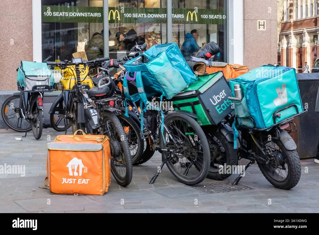 Le biciclette elettriche per la consegna dei pasti sono parcheggiate all'esterno di un ristorante McDonalds, mentre i corrieri attendono di ritirare gli ordini di cibo. Londra Regno Unito. Foto Stock