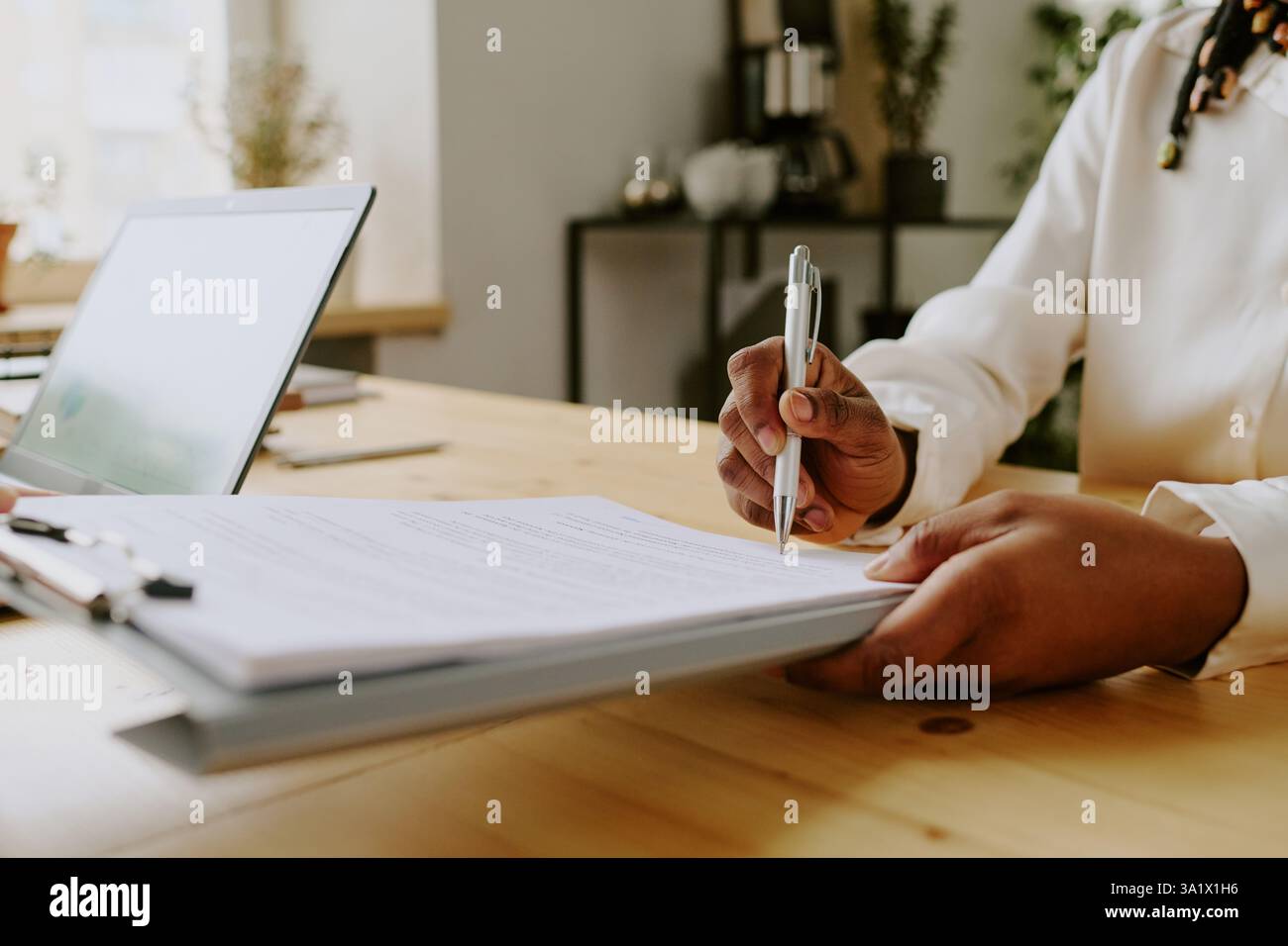 Primo piano medio di una donna irriconoscibile che tiene in mano gli appunti con documenti mentre firma un contatto di lavoro in ufficio Foto Stock
