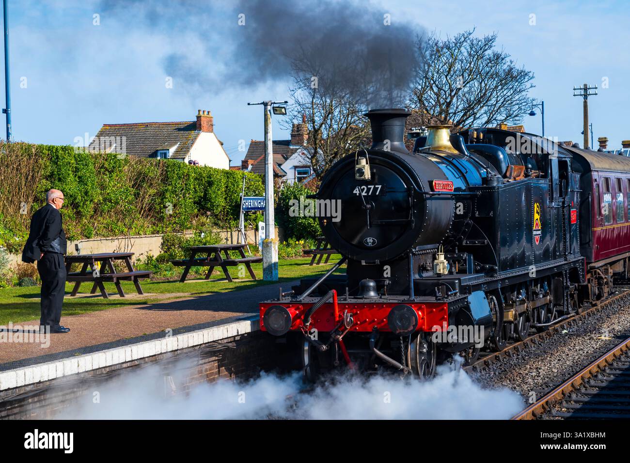 Sheringham, Norfolk, Regno Unito – 8 marzo 2025: Una guardia sbarca dal treno a vapore Hercules parte dalla stazione di Sheringham nel North Norfolk, Regno Unito Foto Stock