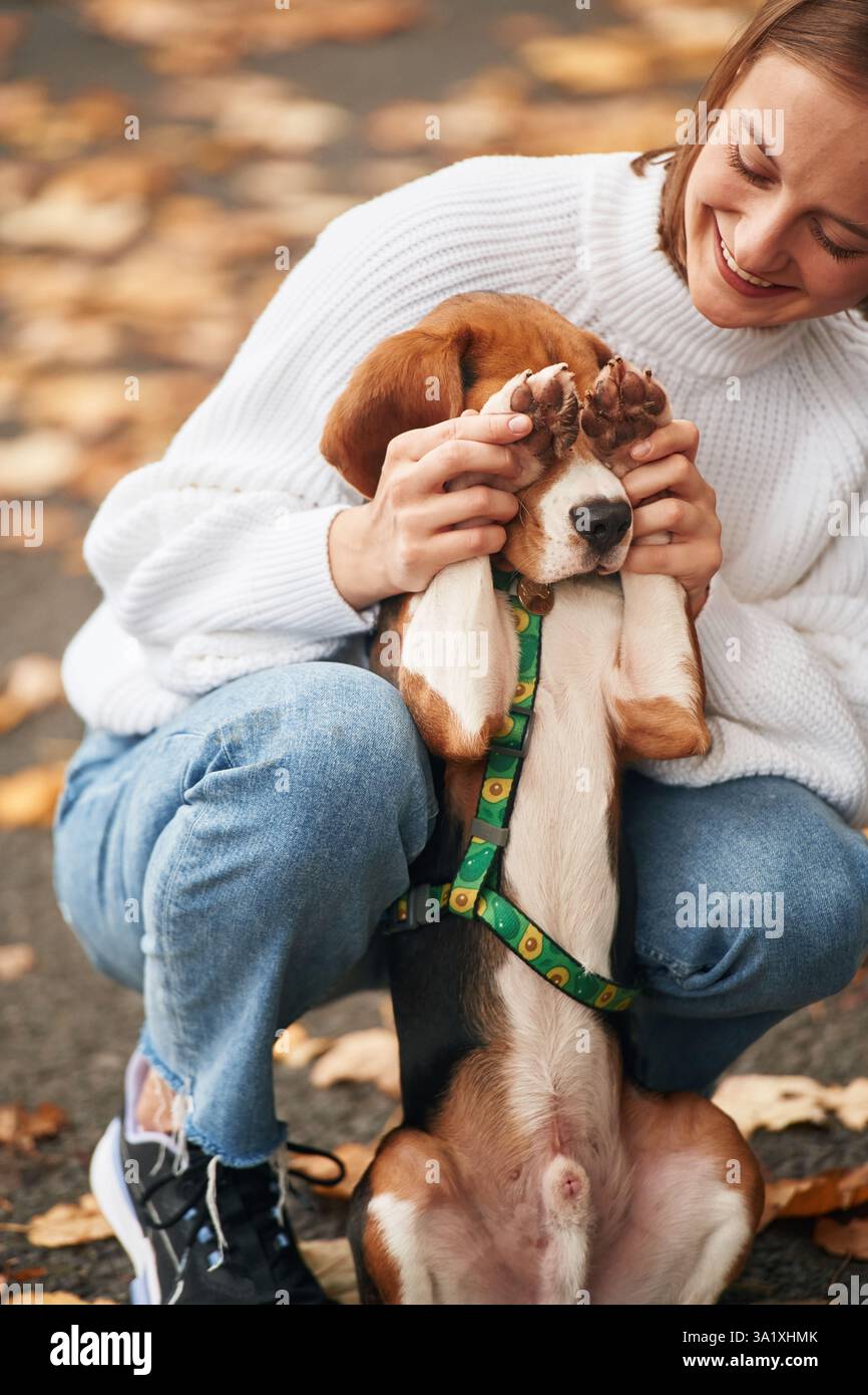 Con zampe che coprono gli occhi. La giovane donna è con il suo cane nel parco. Foto Stock