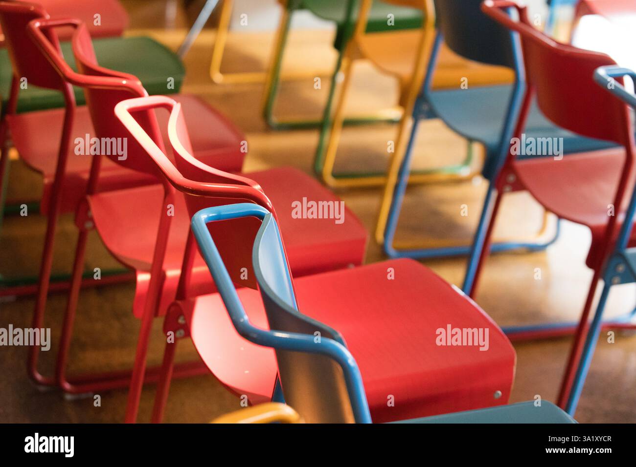 Sedie colorate in una sala riunioni, probabilmente in un museo o in un luogo simile. Molte sedie in vari colori, probabilmente un allestimento temporaneo. Foto Stock