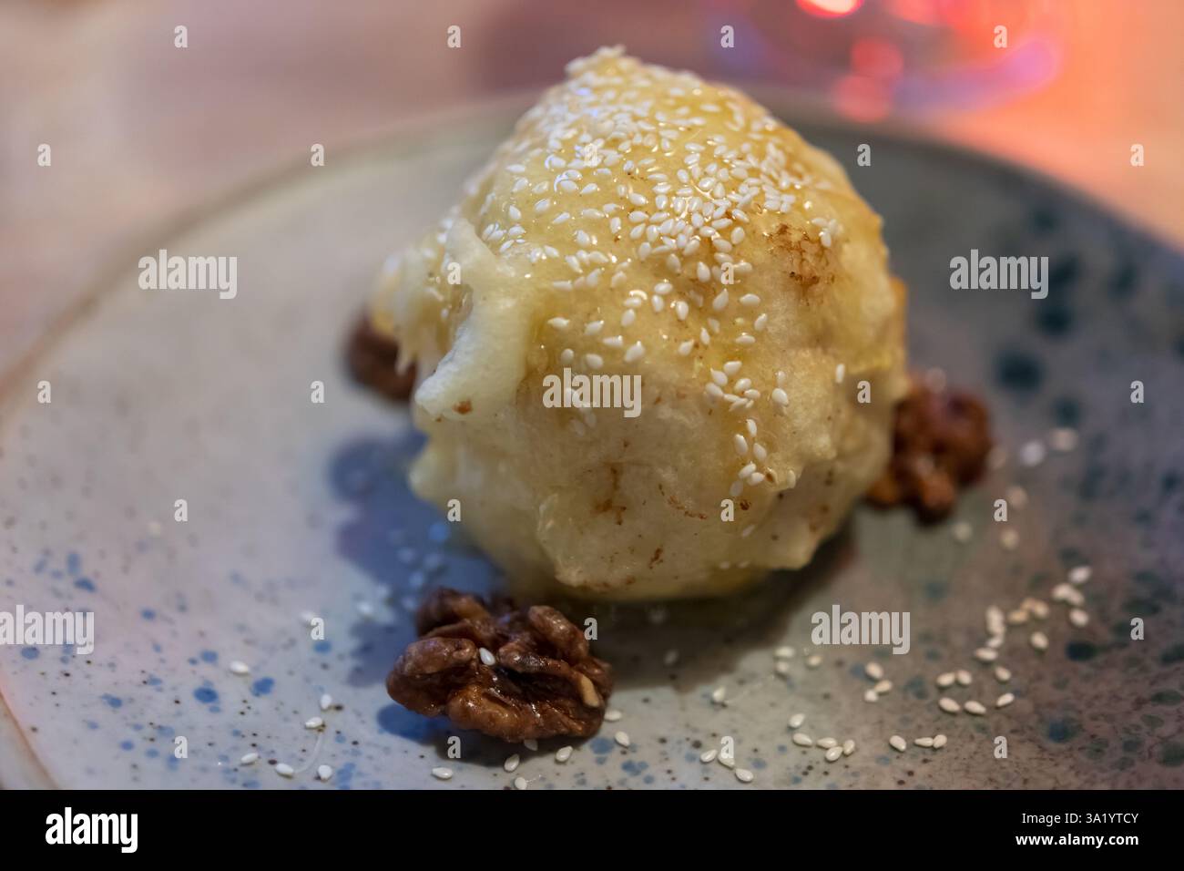 Delizioso gelato fritto giapponese, dorato e croccante, cosparso di miele e cosparso di semi di sesamo. Il dessert è servito su un elegante piatto W. Foto Stock