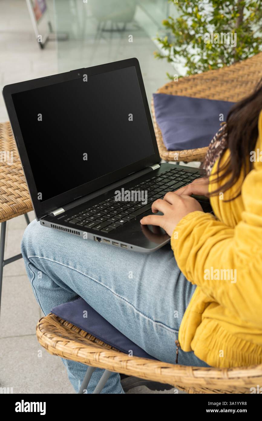Un momento di concentrazione quando una ragazza accende il suo portatile per iniziare a studiare per l'esame universitario, preparandosi per una lunga sessione di studio piena di deterrenti Foto Stock