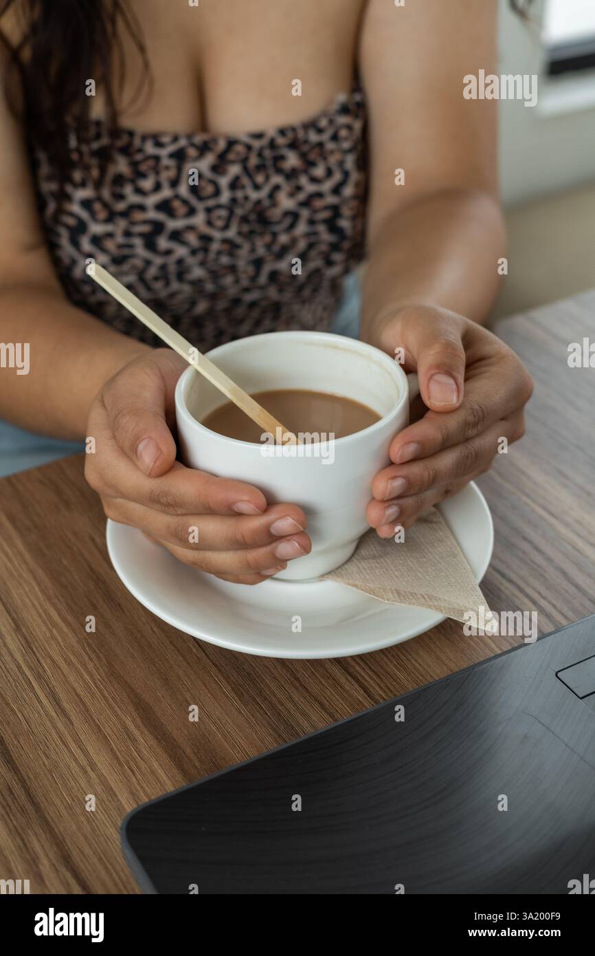Un momento tenero e romantico mentre le mani cullano dolcemente una tazza di cremosa cioccolata calda, assaporando il suo calore e dolcezza, perduti nell'intimità del momento, Foto Stock
