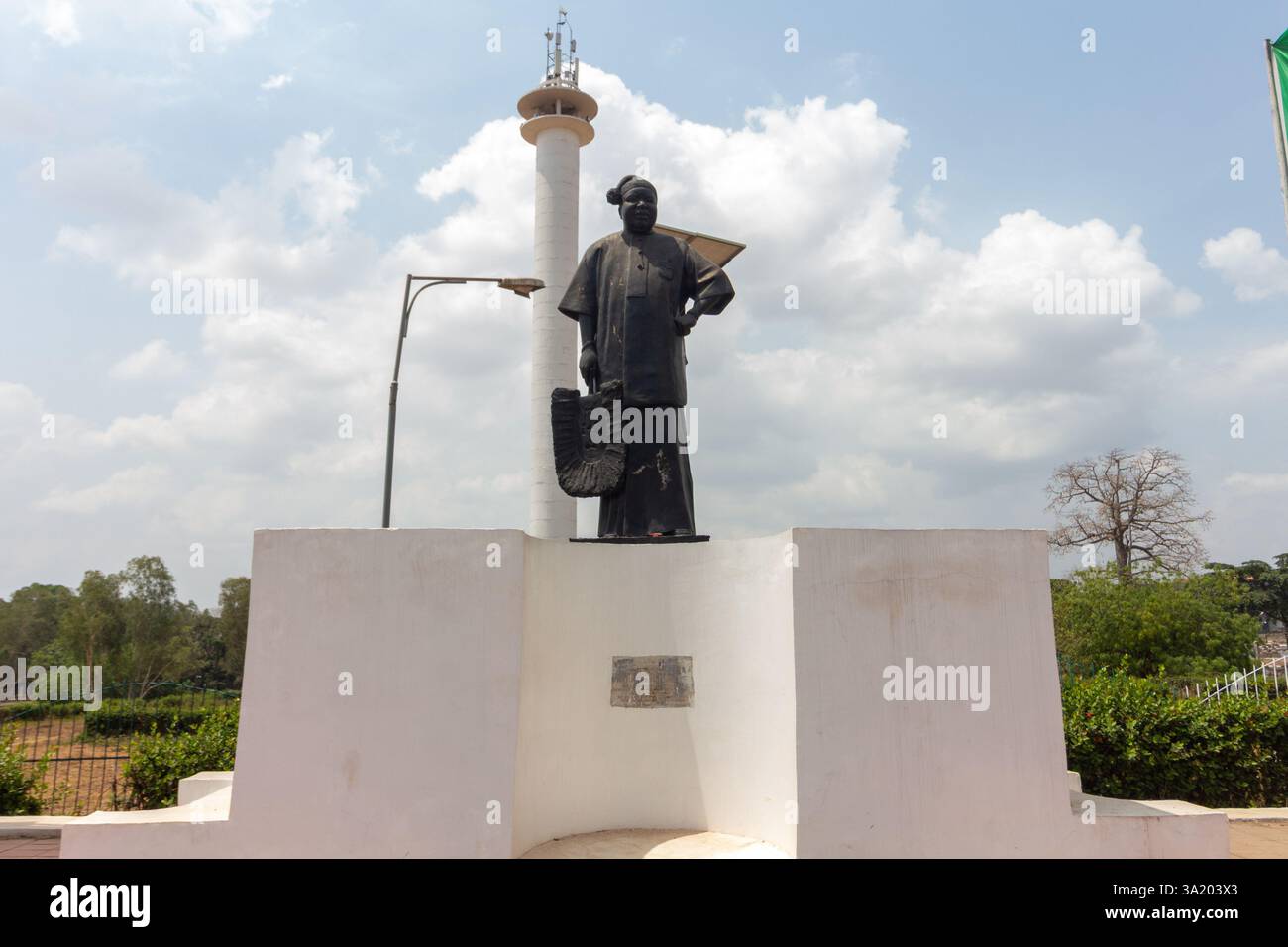 Monumento a Enugu, Nigeria, con una figura di Michael Okpara su un piedistallo con bandiere e una torre sullo sfondo. Marzo 2025 Foto Stock