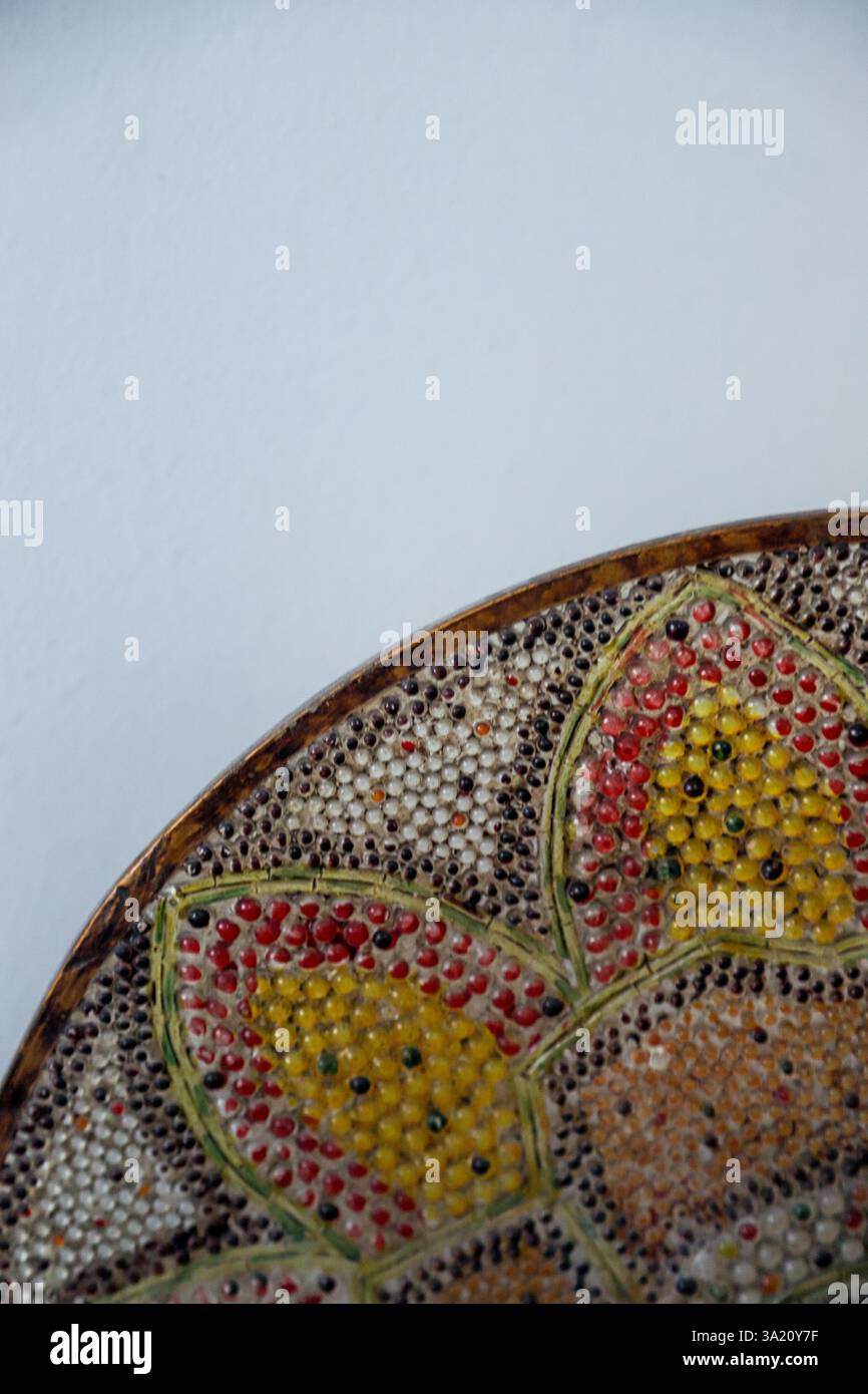 La ciotola decorativa presenta un design floreale meticolosamente realizzato con vivaci tonalità di rosso, giallo e terra su uno sfondo semplice, Highlight Foto Stock