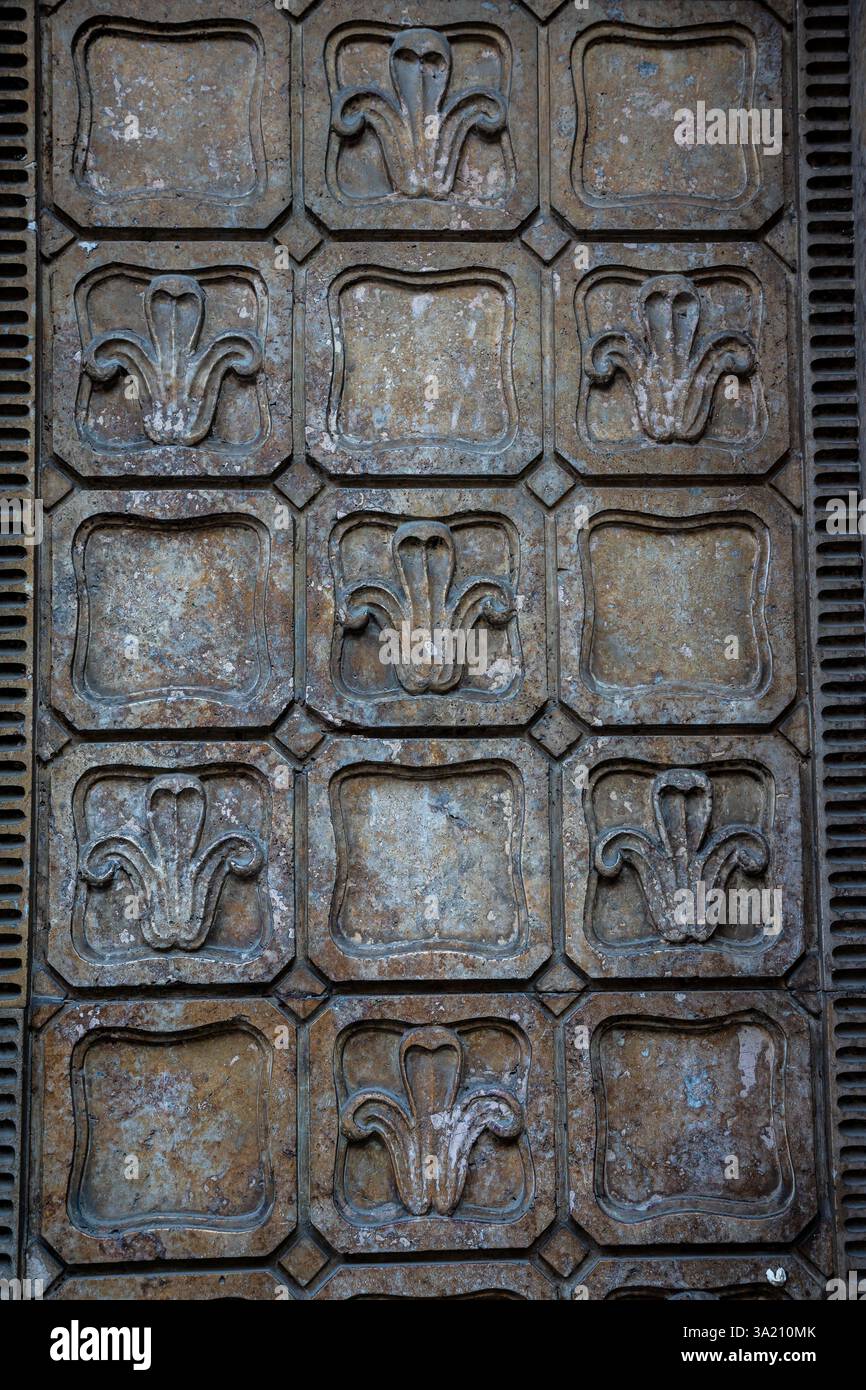Una vista ravvicinata di un pannello decorativo a parete che mostra disegni floreali ornati, evidenziando la cura artigianale dettagliata e la superficie intemprata in una vecchia b Foto Stock Una vista ravvicinata di un pannello decorativo a parete che mostra disegni floreali ornati, evidenziando la cura artigianale dettagliata e la superficie intemprata in una vecchia b Foto Stock