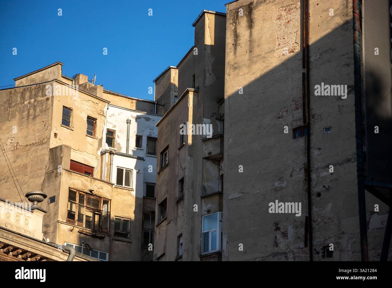 Il paesaggio urbano di Bucarest presenta edifici storici con diverse texture e finestre illuminate da un cielo blu luminoso, che enfatizza l'architettura Foto Stock