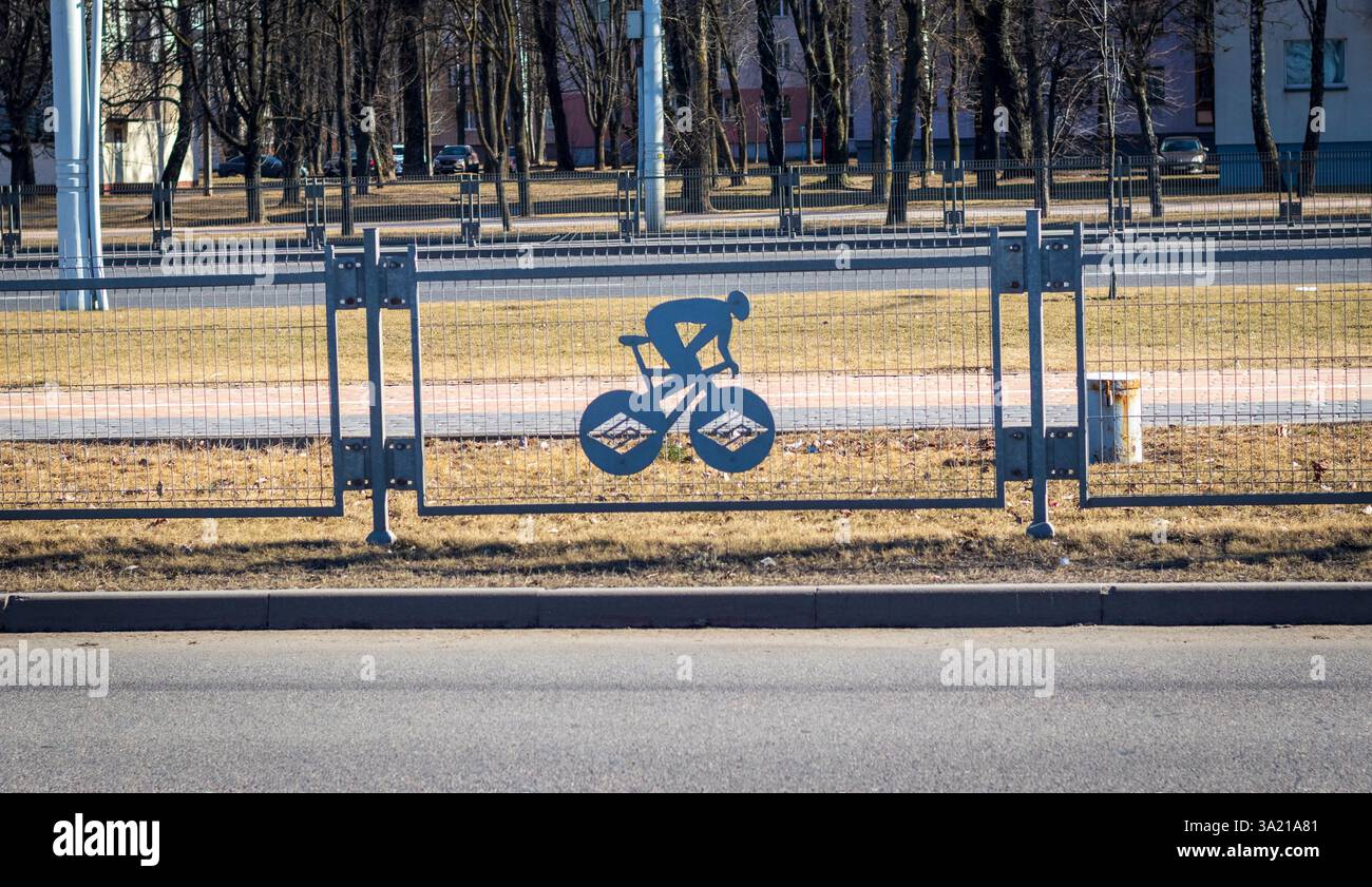 La recinzione separa il traffico bidirezionale con ornamenti decorativi legati allo sport Foto Stock