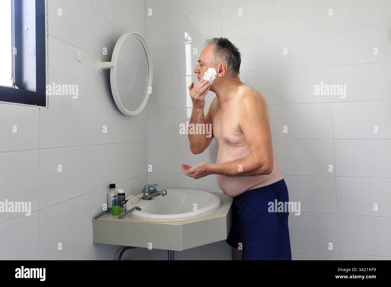 Man 60 Plus si rasa bagnato in bagno Foto Stock