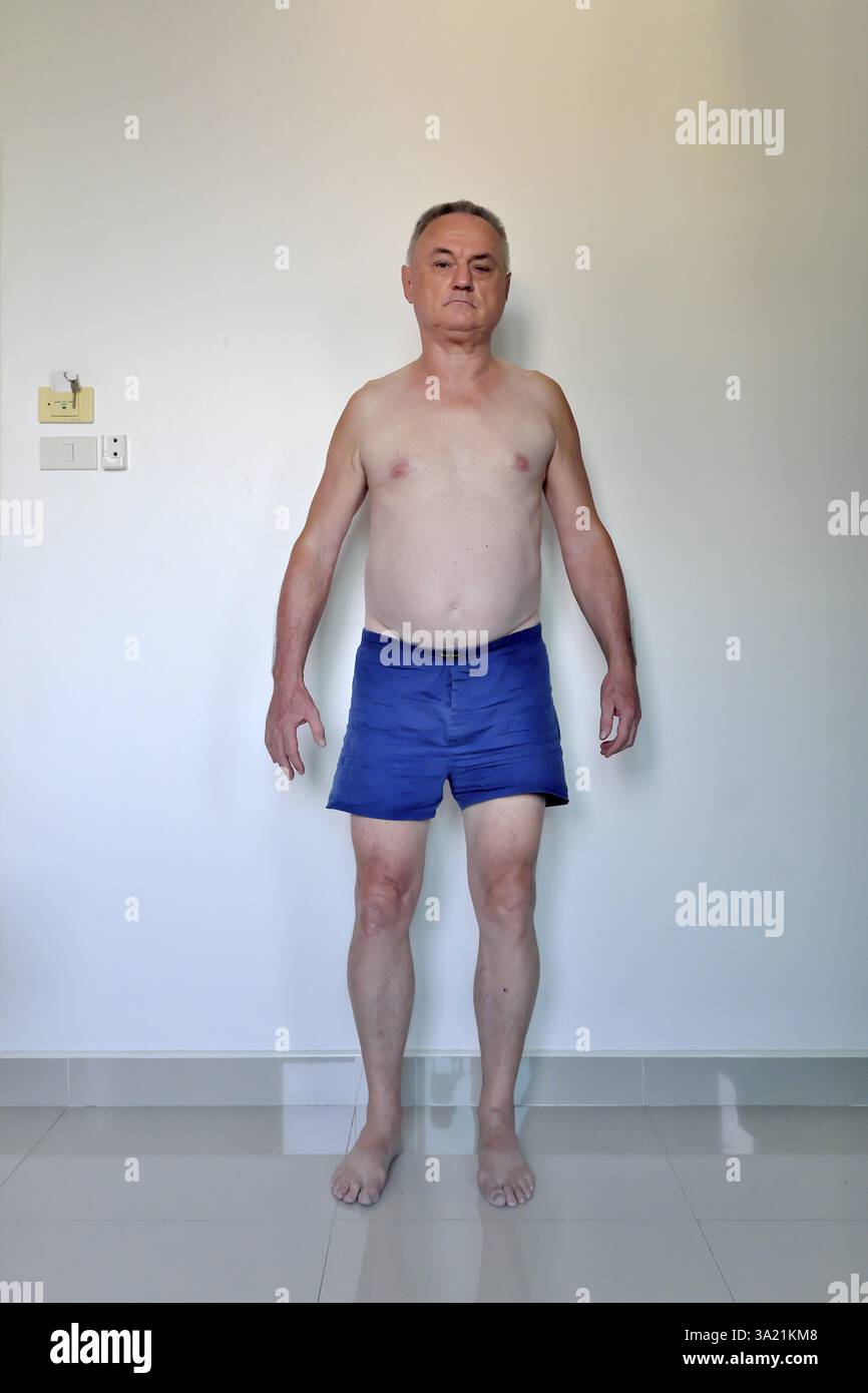 Uomo 60 Plus con pantaloncini da pugile davanti al muro bianco, Pattaya, Chonburi, Thailandia, Asia Foto Stock