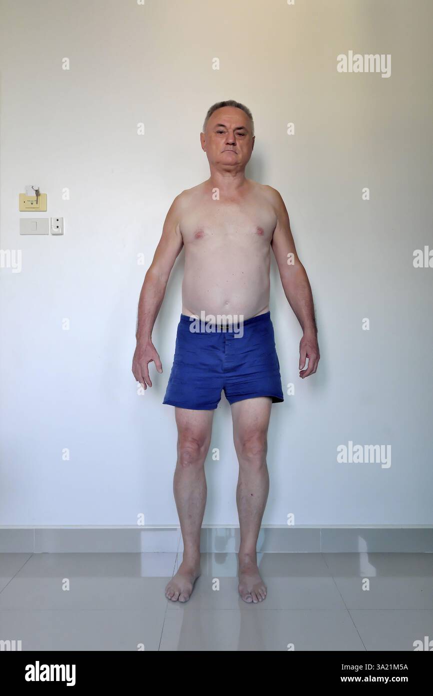 Uomo 60 Plus con pantaloncini da pugile davanti al muro bianco, Pattaya, Chonburi, Thailandia, Asia Foto Stock
