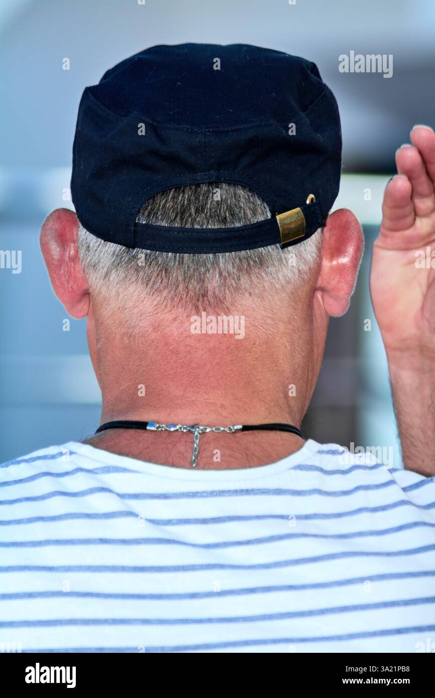 Momento casual, quando un uomo alza la mano da dietro, con capelli corti e una camicia a righe, su un morbido sfondo esterno. Foto Stock Momento casual, quando un uomo alza la mano da dietro, con capelli corti e una camicia a righe, su un morbido sfondo esterno. Foto Stock