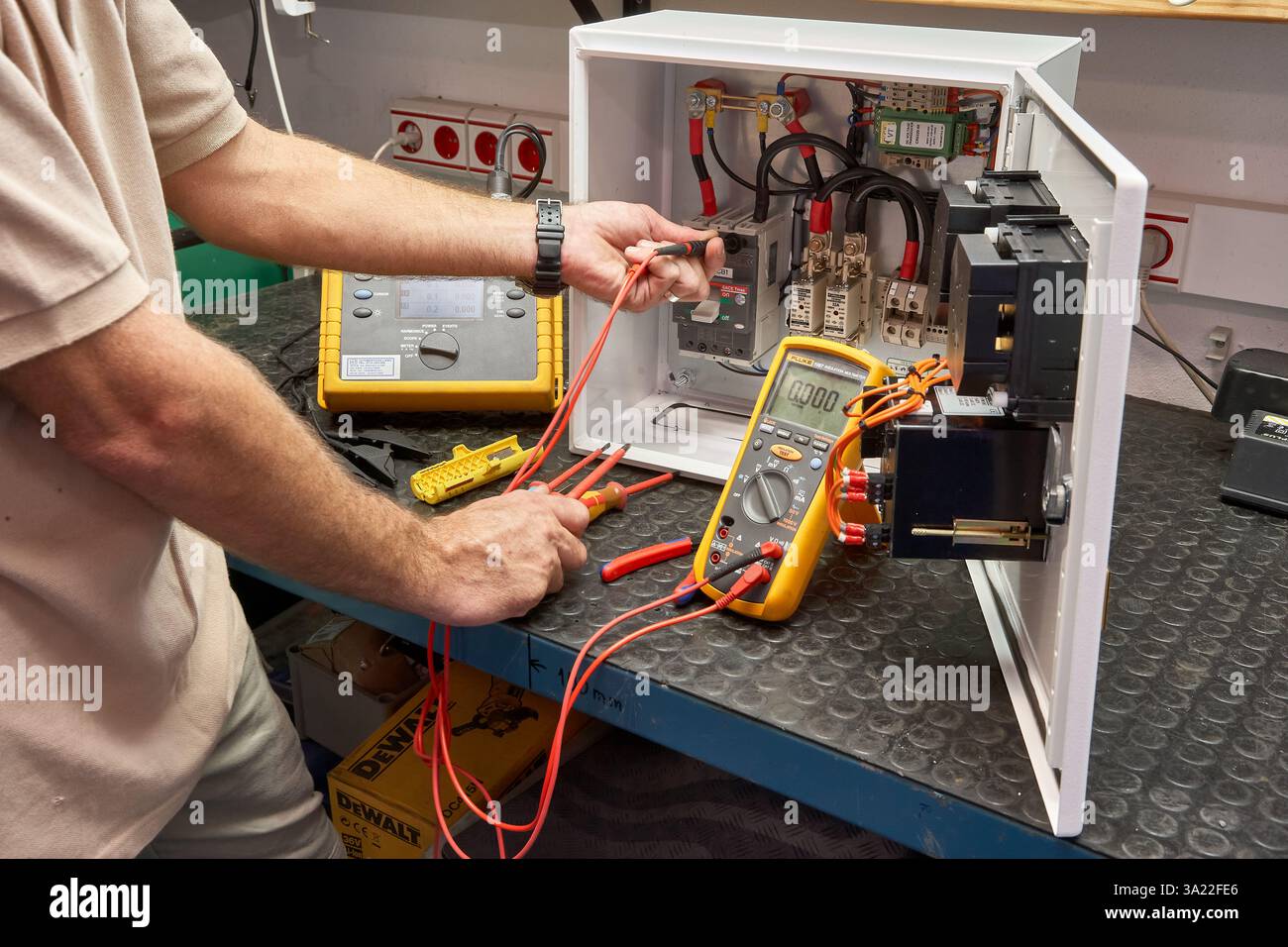 Tecnico che esegue il test delle apparecchiature elettriche utilizzando un multimetro e strumenti professionali Foto Stock