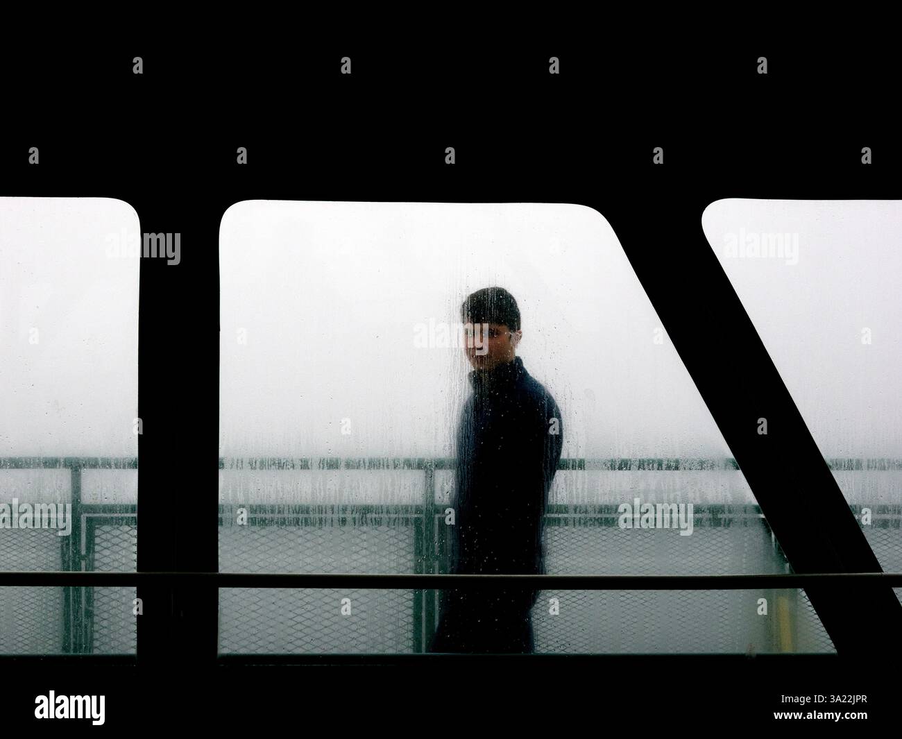 WA26400-00...... WASHINGTON - persona solitaria che cammina sul ponte superiore del traghetto Edmonds Kingston in una giornata di pioggia. Foto Stock
