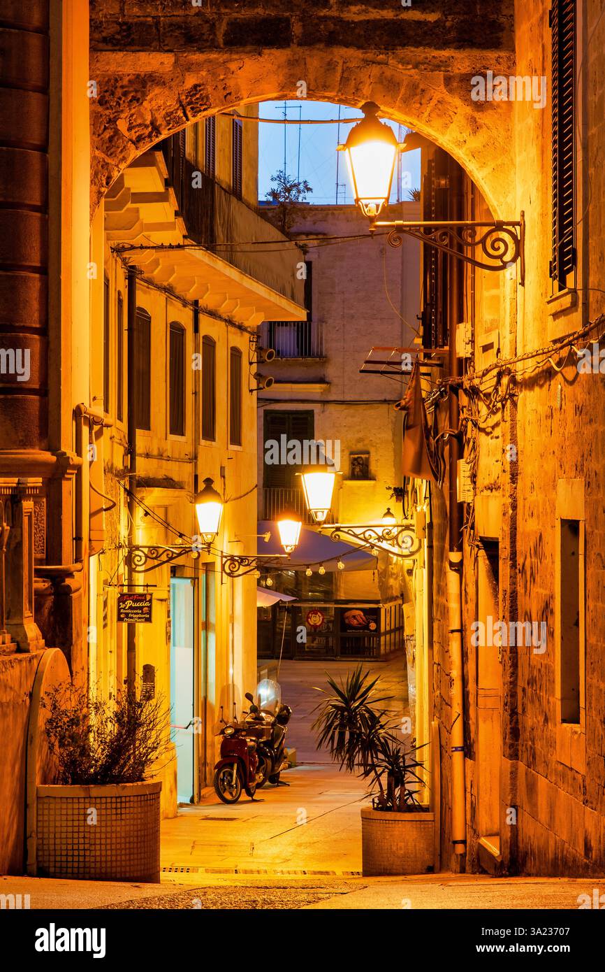 Vicolo vicino a Piazza Mercantile illuminato dai lampioni notturni a Bari Vecchia, Bari, Italia. Foto Stock