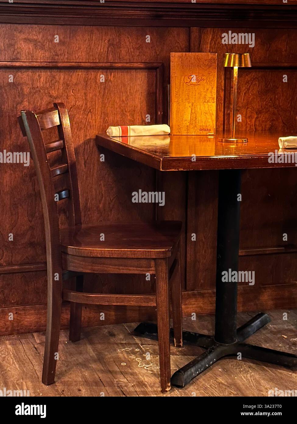 Una scena intima ma solitaria di una sedia e una lampada in legno che proietta ombre delicate in un ambiente rustico - Immagine stock catturata con smartphone
