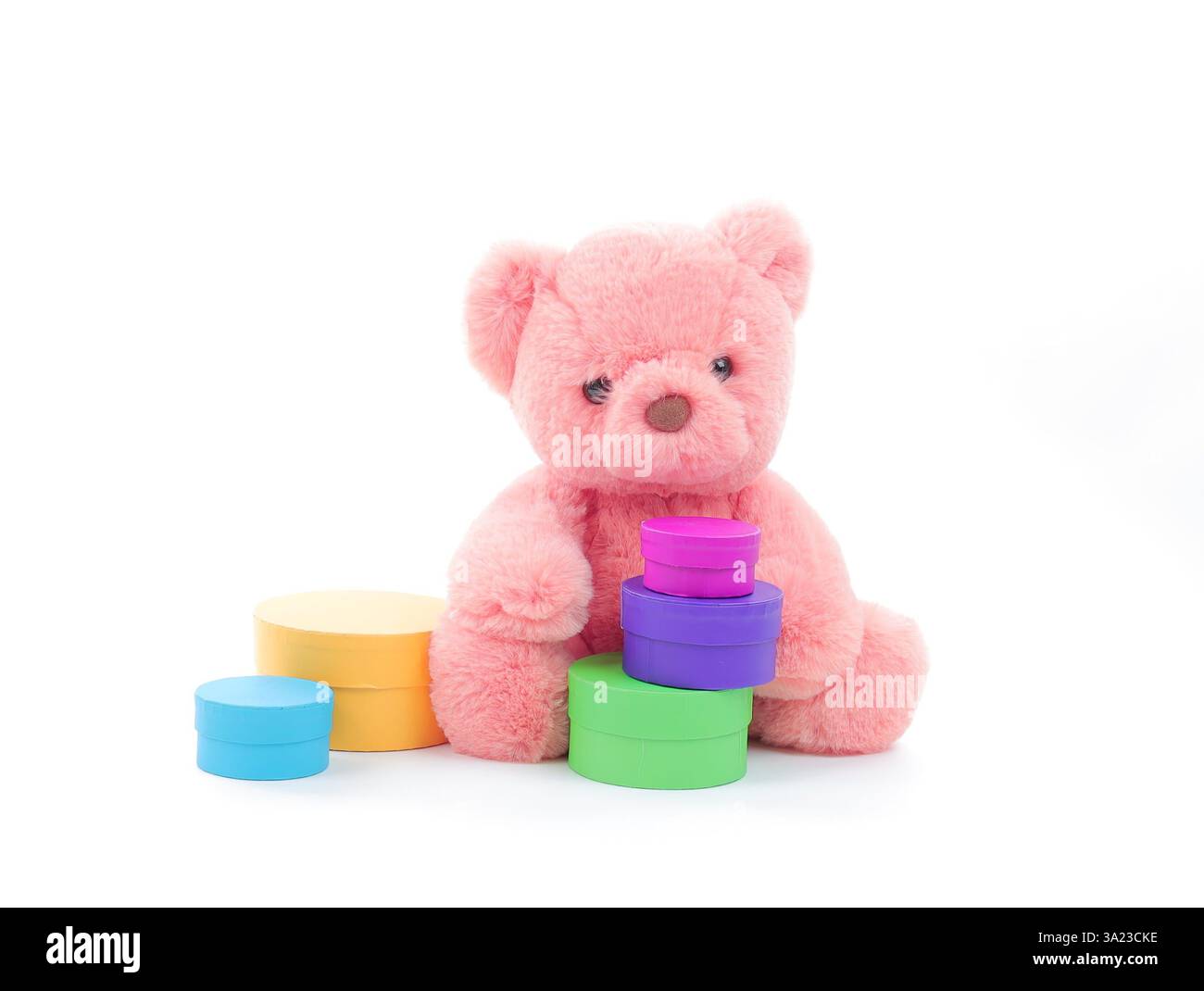 Simpatico orsacchiotto corallino rosa con un set di scatole multicolore su sfondo bianco puro con spazio per le copie del testo Foto Stock