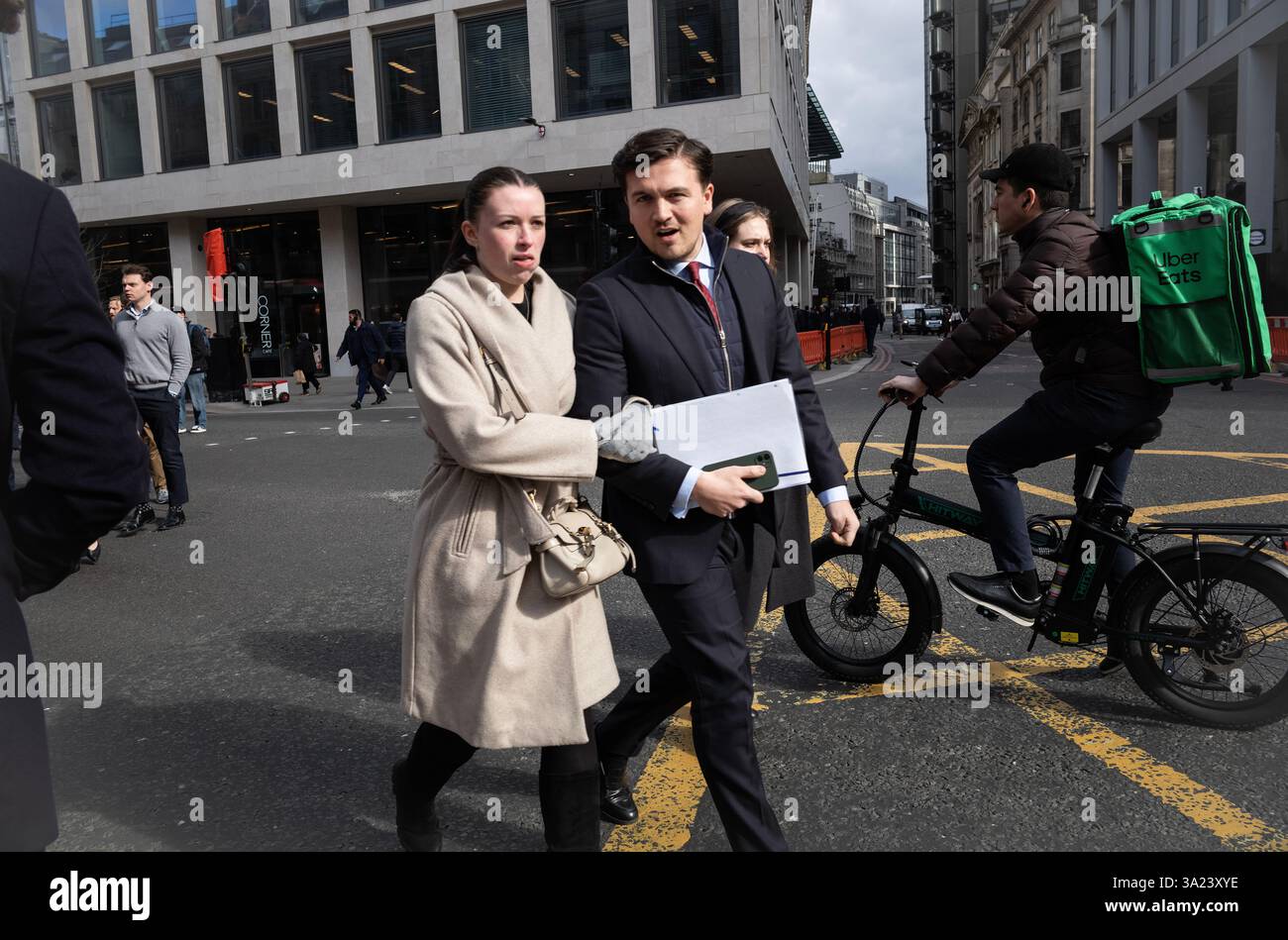 Una giovane coppia cammina a braccio lungo Bishopsgate durante il pranzo di mezzogiorno, mentre i lavoratori si godono un po' di sole primaverile, City of London, Inghilterra, Regno Unito Foto Stock