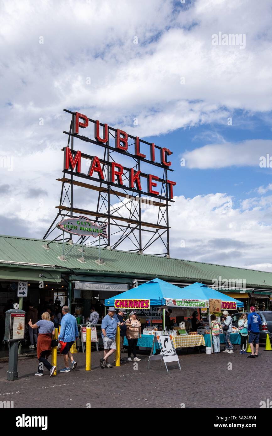 I turisti e la gente del posto acquistano prodotti freschi al Pike Place Market di Seattle, Washington, sostenendo gli agricoltori e le aziende locali. Foto Stock