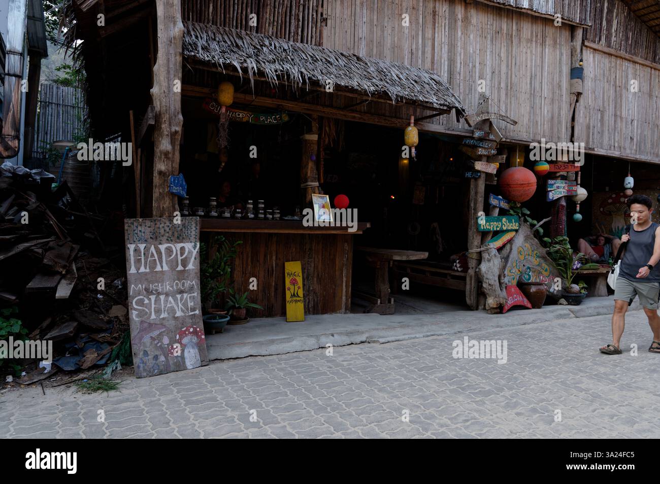 Bar rustico in bambù con tetto in paglia e colorate insegne fatte a mano che pubblicizzano "Happy Mushroom Shake" Foto Stock