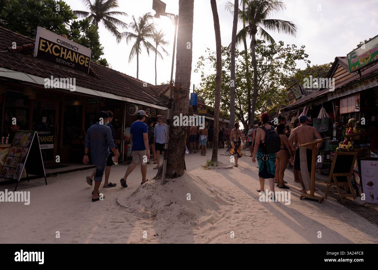 I turisti camminano sotto il caldo sole pomeridiano lungo una strada sabbiosa a Railay Foto Stock