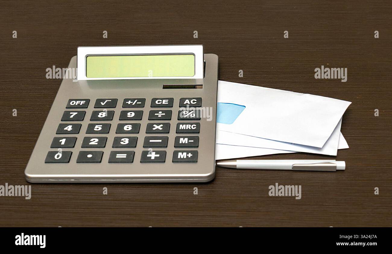 Pile di buste di carta bianca chiuse vuote e calcolatrice elettrica su un lato Foto Stock