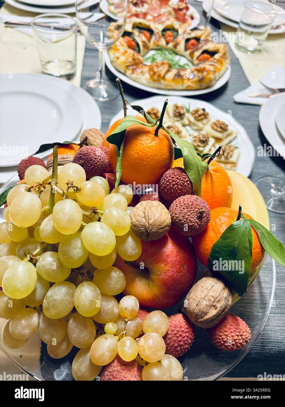 Vari tipi di frutta (uva, mele, noci, litchi, arance) su una tavola di Natale. Festività e Natale. Direttamente sopra. Foto Stock