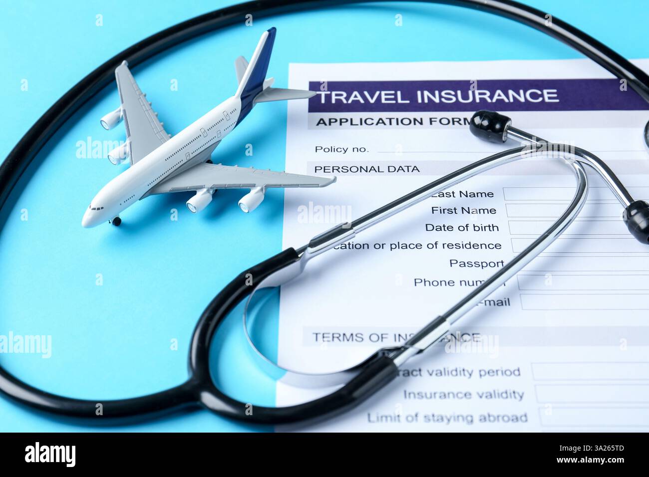 Turismo medico. Modulo di richiesta assicurazione di viaggio, stetoscopio e modello aereo su sfondo azzurro, primo piano Foto Stock