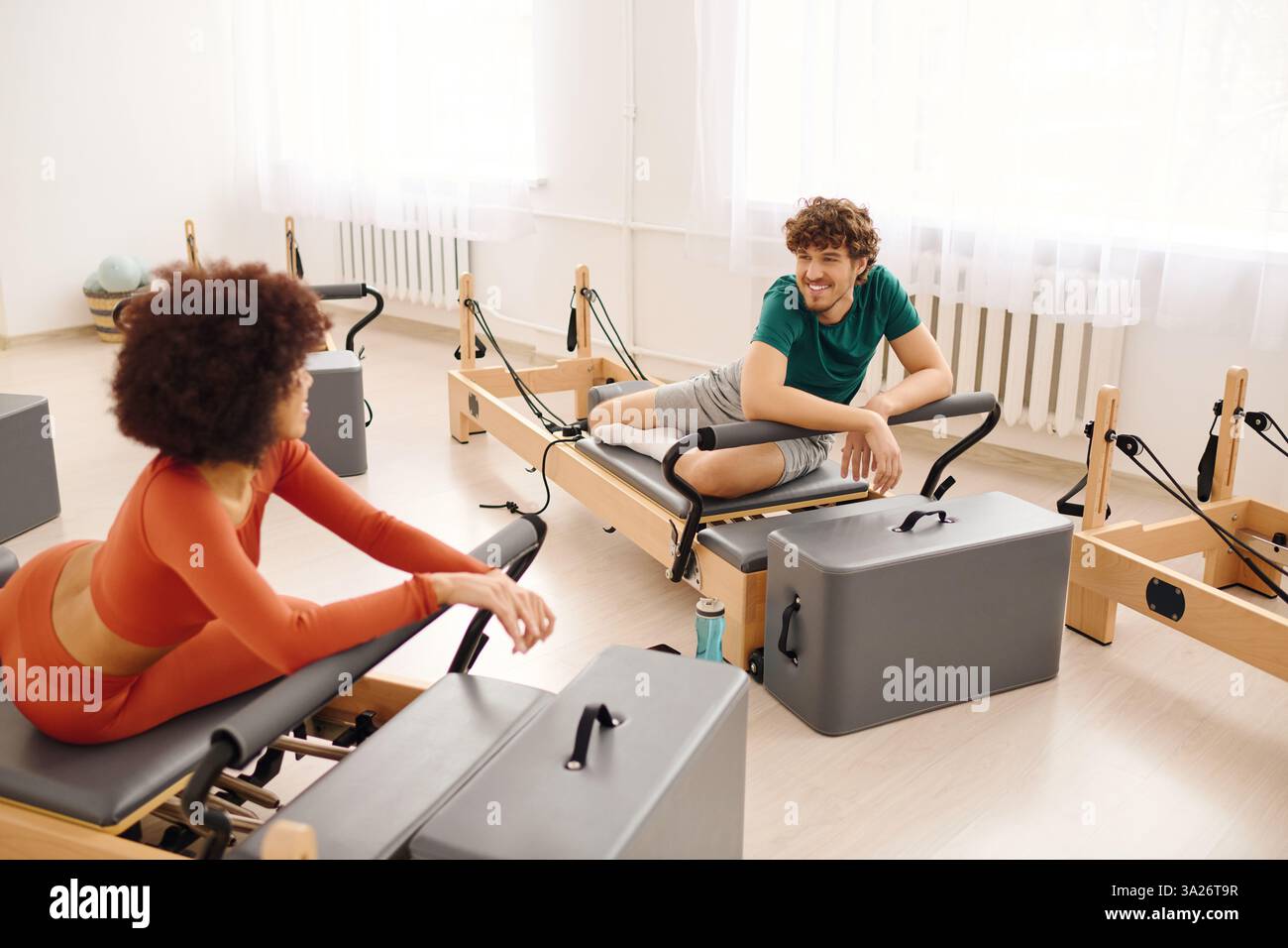 Due persone si allenano a Pilates in uno studio luminoso, scambiandosi sorrisi e motivazione. Foto Stock Due persone si allenano a Pilates in uno studio luminoso, scambiandosi sorrisi e motivazione. Foto Stock