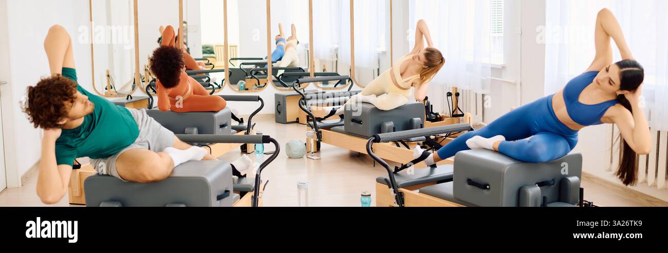 Gruppo di individui impegnati in esercizi dinamici di pilates in uno studio luminoso e spazioso. Foto Stock