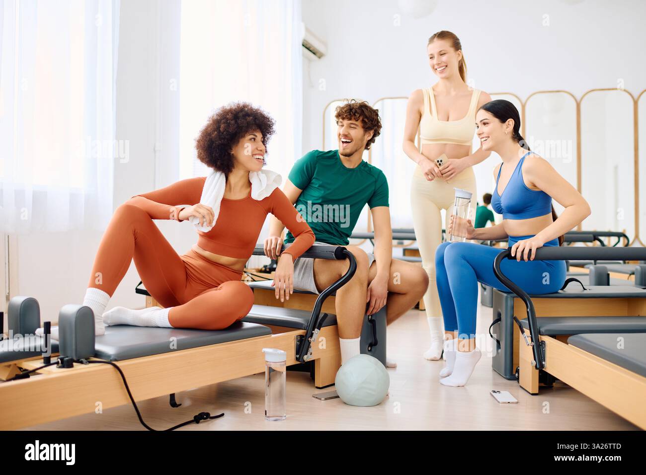 Coinvolgente gruppo di persone ama una sessione di allenamento in un vivace ambiente di studio pilates Foto Stock