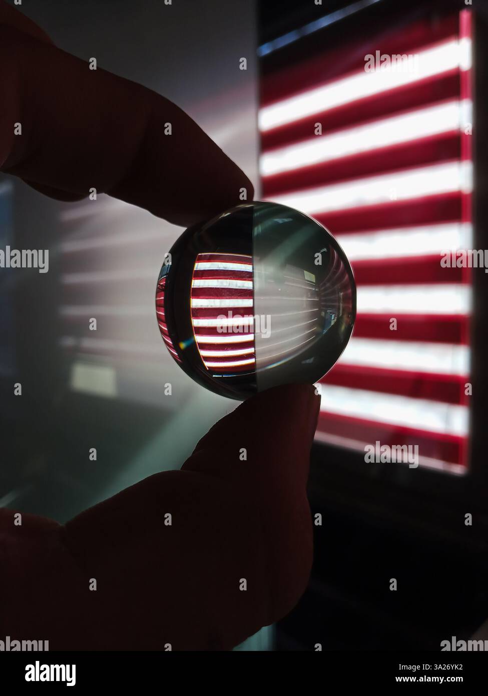 sfera di cristallo che riflette le tende a strisce rosse e bianche, creando un'illusione ottica con luce e ombre Foto Stock
