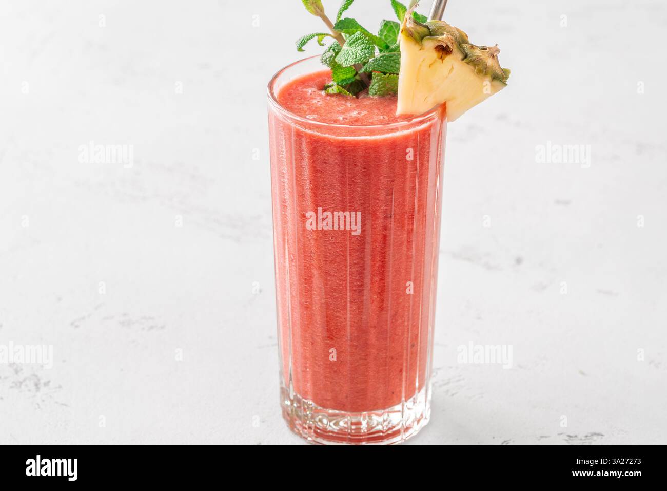 Frullato tropicale cremoso con ciliegia, banana e ananas, guarnito con menta e ananas Foto Stock