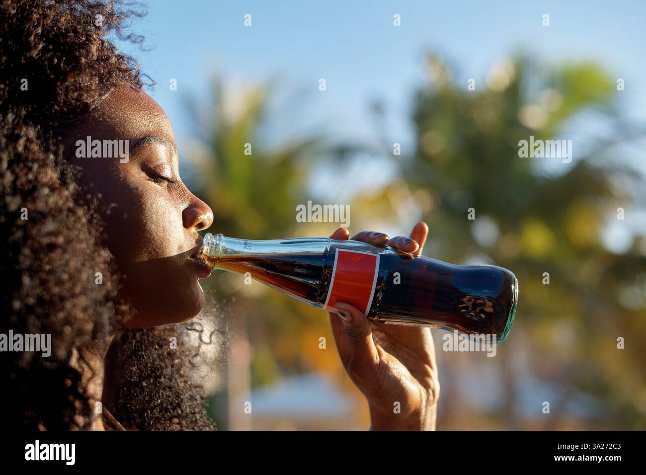 Donna che beve una bevanda rinfrescante da una bottiglia di vetro all'aperto con il sole. Miami, Florida, Stati Uniti Foto Stock