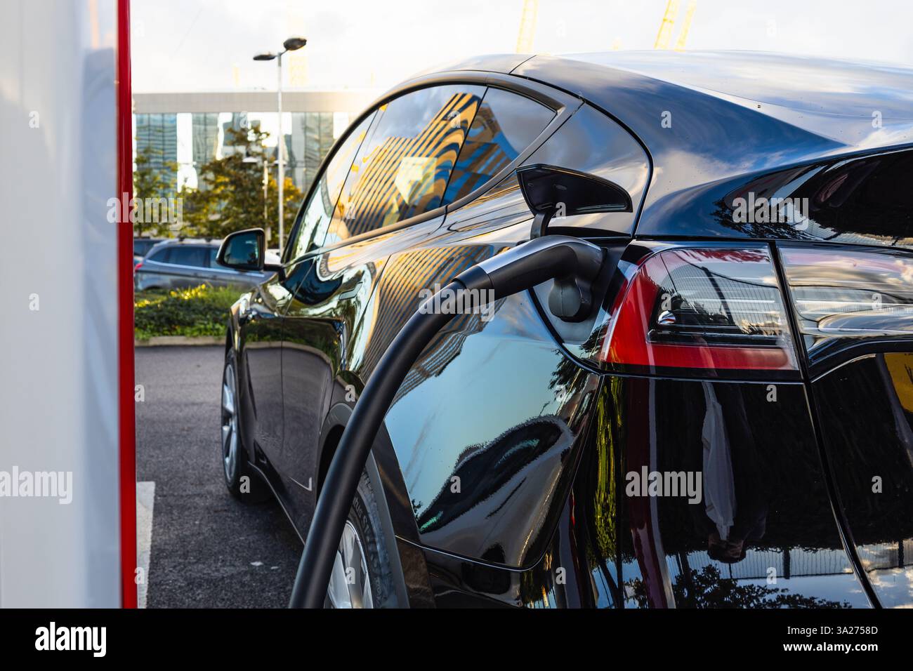 Ricarica di un'auto elettrica presso un Supercharger Tesla, simbolo della mobilità sostenibile Foto Stock