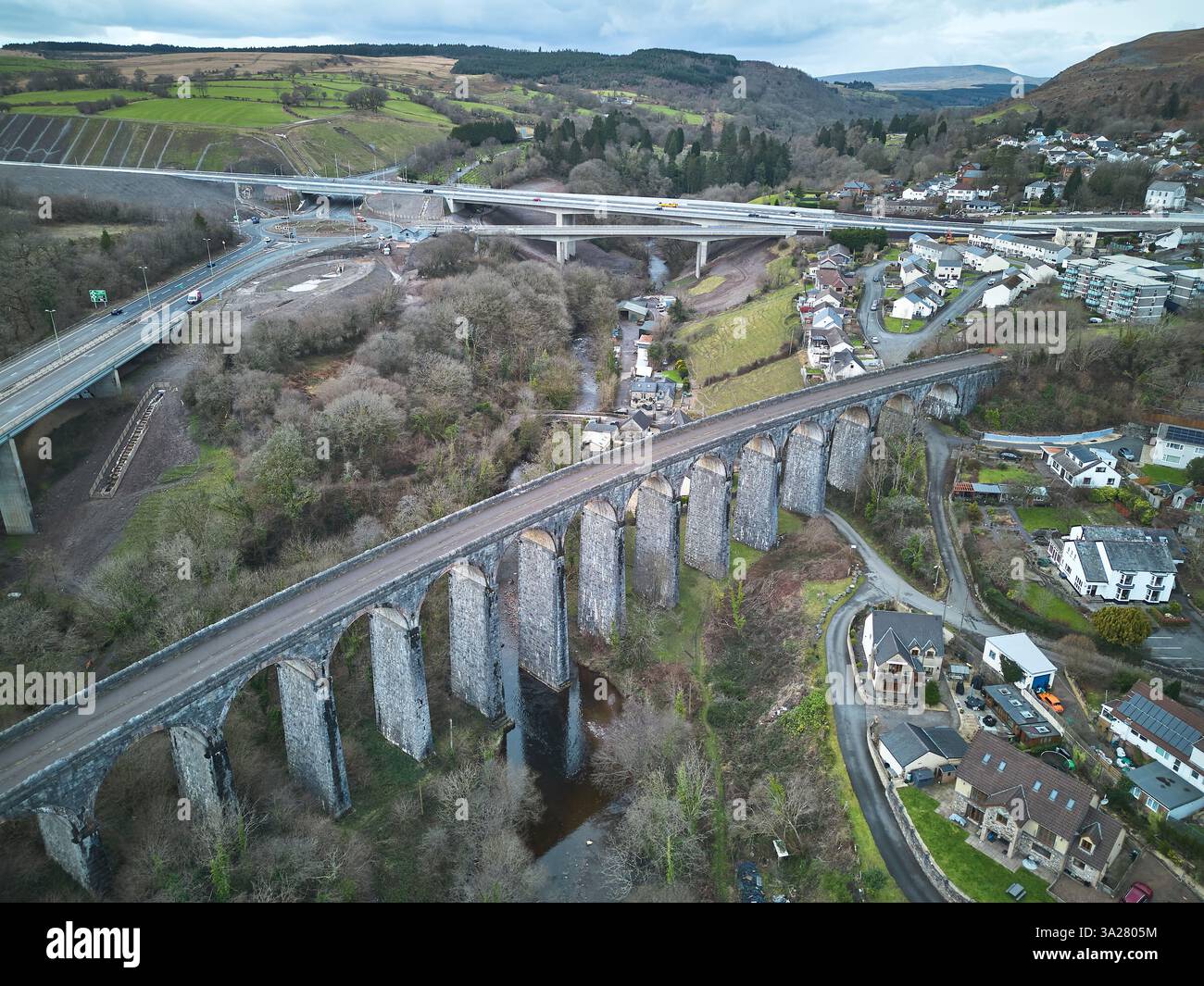 Viadotto ferroviario in disuso sul fiume Taf in Galles, con la strada Heads of the Valleys sullo sfondo Foto Stock