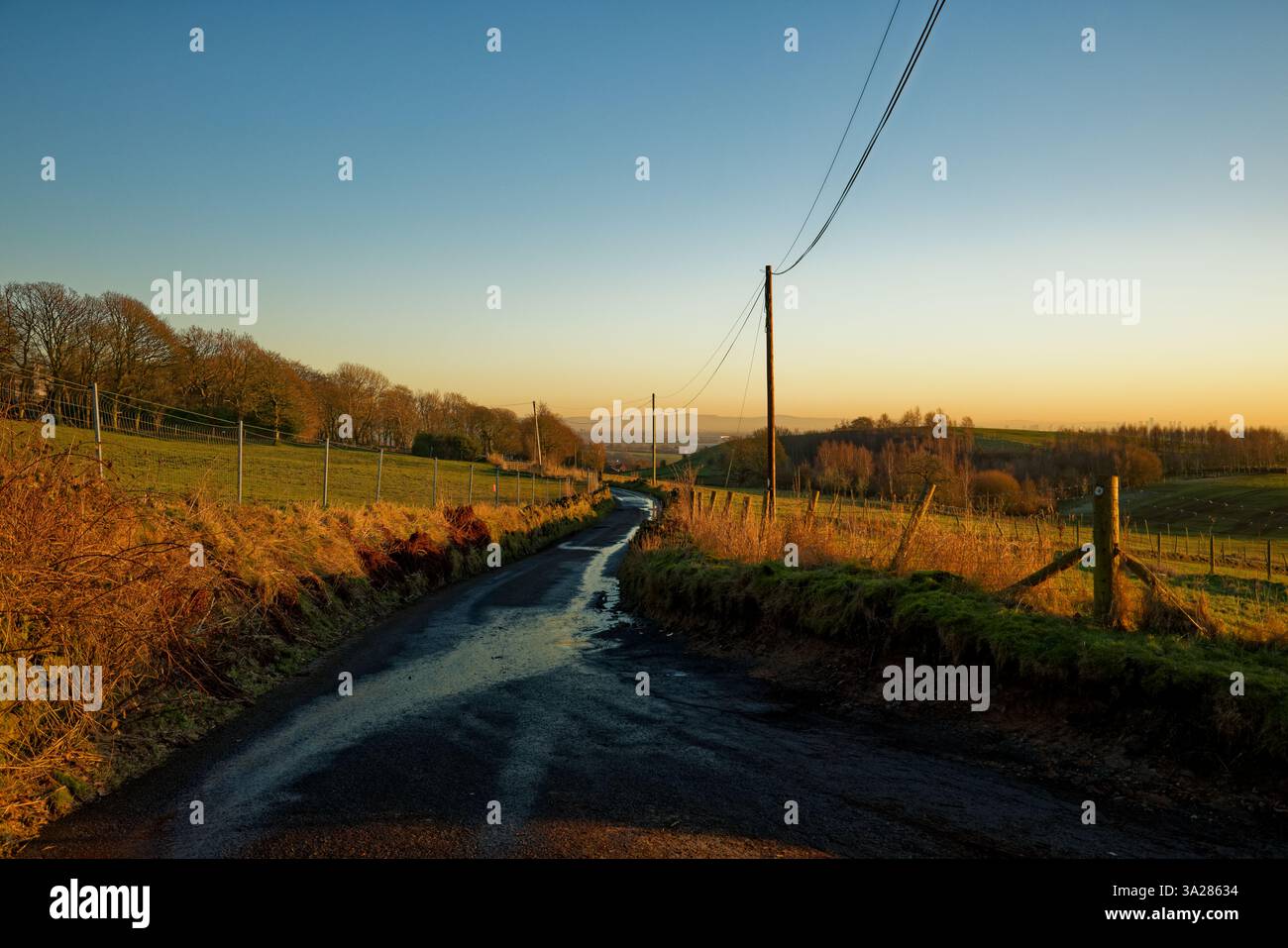Una strada rurale con il tramonto che si avvicina alla fine di una giornata invernale, Bury, Greater Manchester. Foto Stock