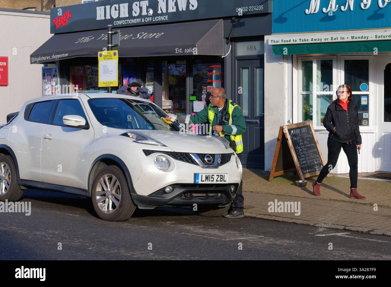 Un addetto al parcheggio o un addetto al traffico. Emissione di un avviso di penalità per un'auto parcheggiata in una strada periferica, Shepperton Surrey, Inghilterra, Regno Unito Foto Stock