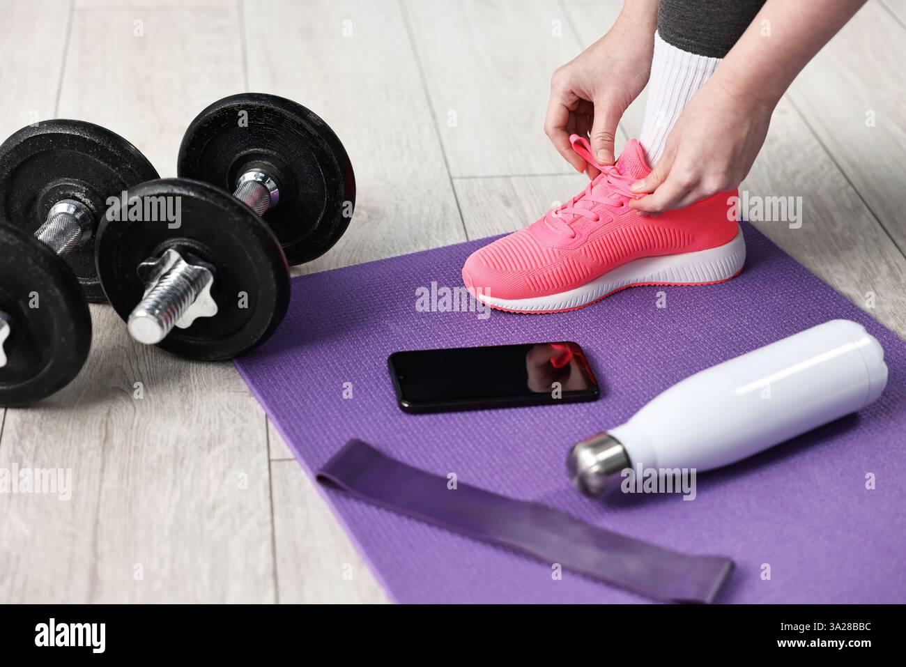 Donna che lega scarpe e attrezzature da palestra al piano interno, primo piano Foto Stock