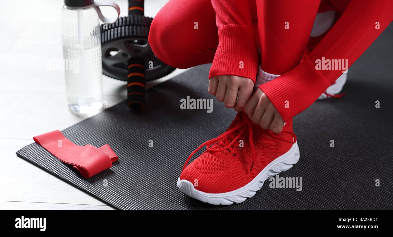 Donna che lega scarpe e attrezzature da palestra al chiuso, primo piano Foto Stock