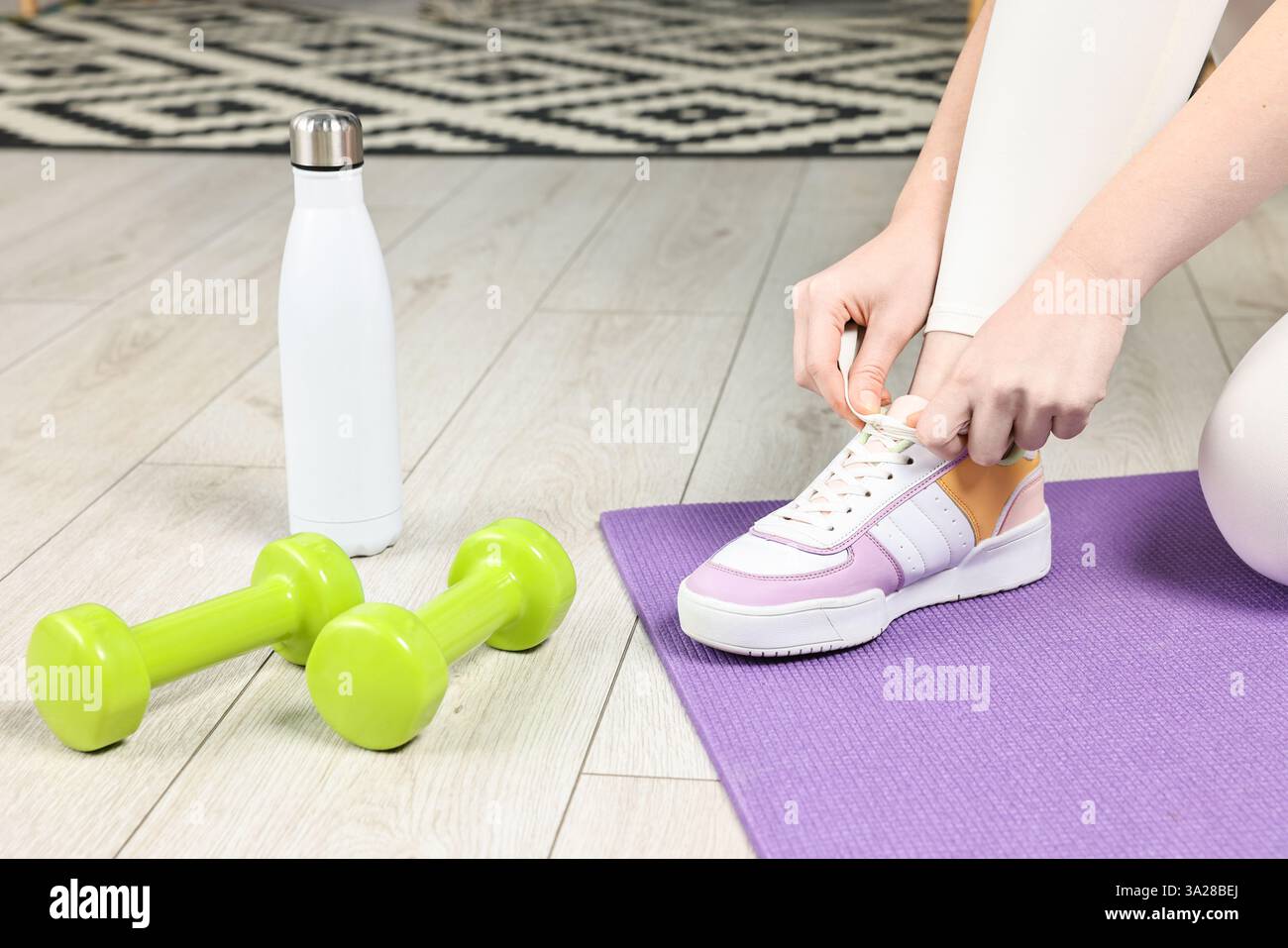 Donna che lega scarpe e attrezzature da palestra al chiuso, primo piano Foto Stock