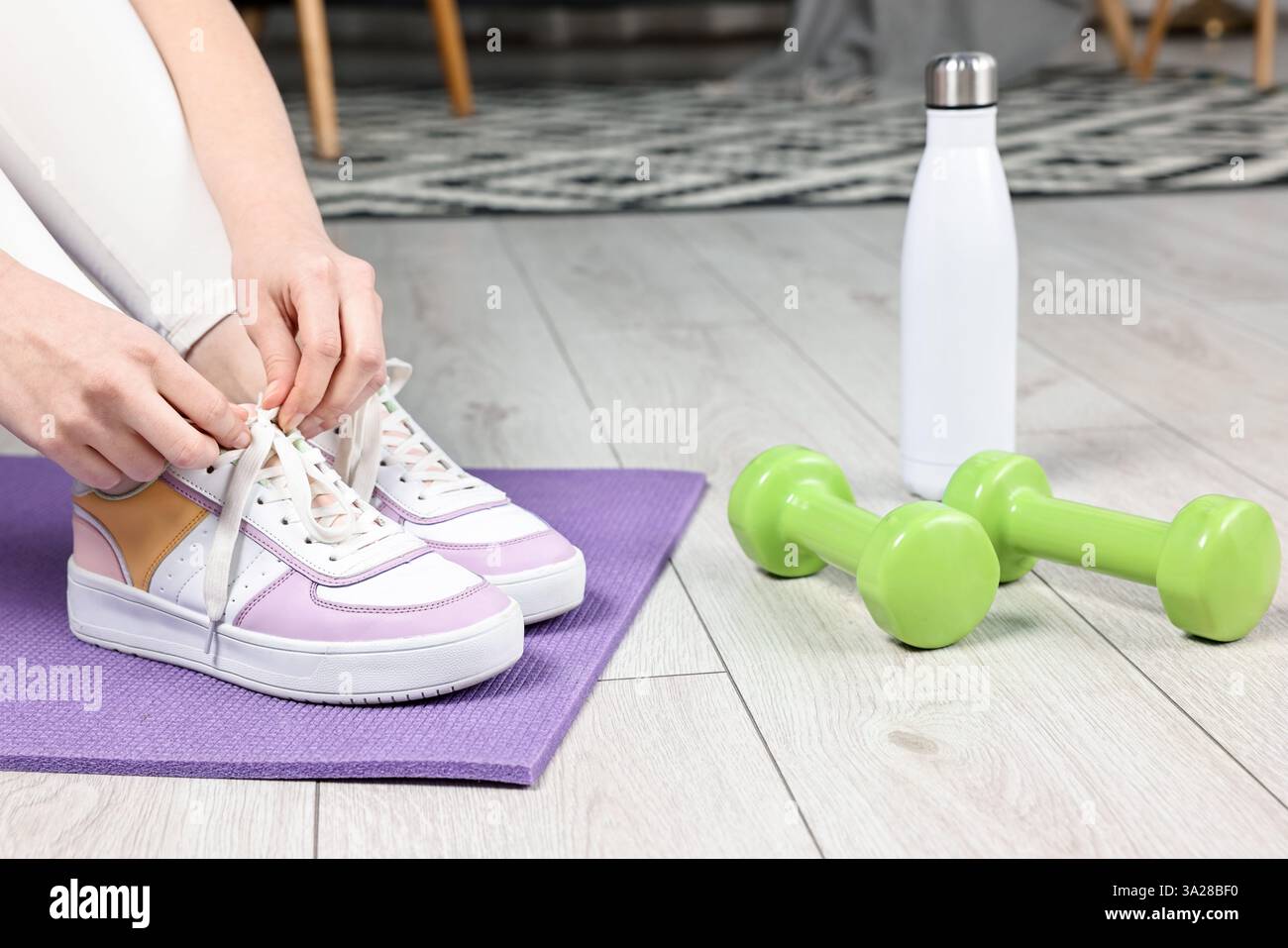 Donna che lega scarpe e attrezzature da palestra al chiuso, primo piano Foto Stock