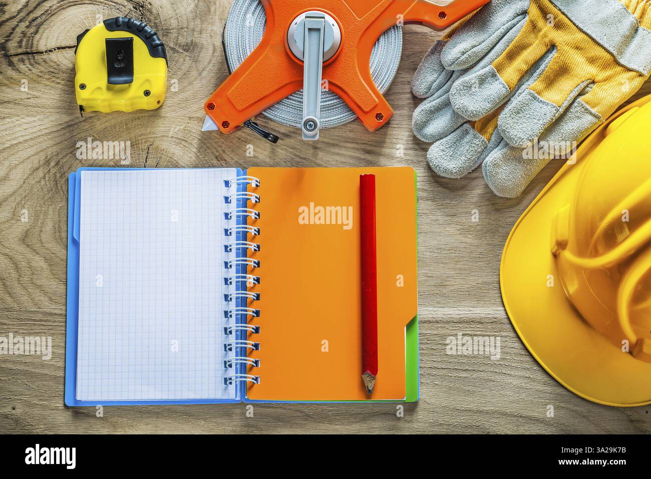 Set di guanti di sicurezza a matita per notebook, casco da costruzione su tavola di legno Foto Stock