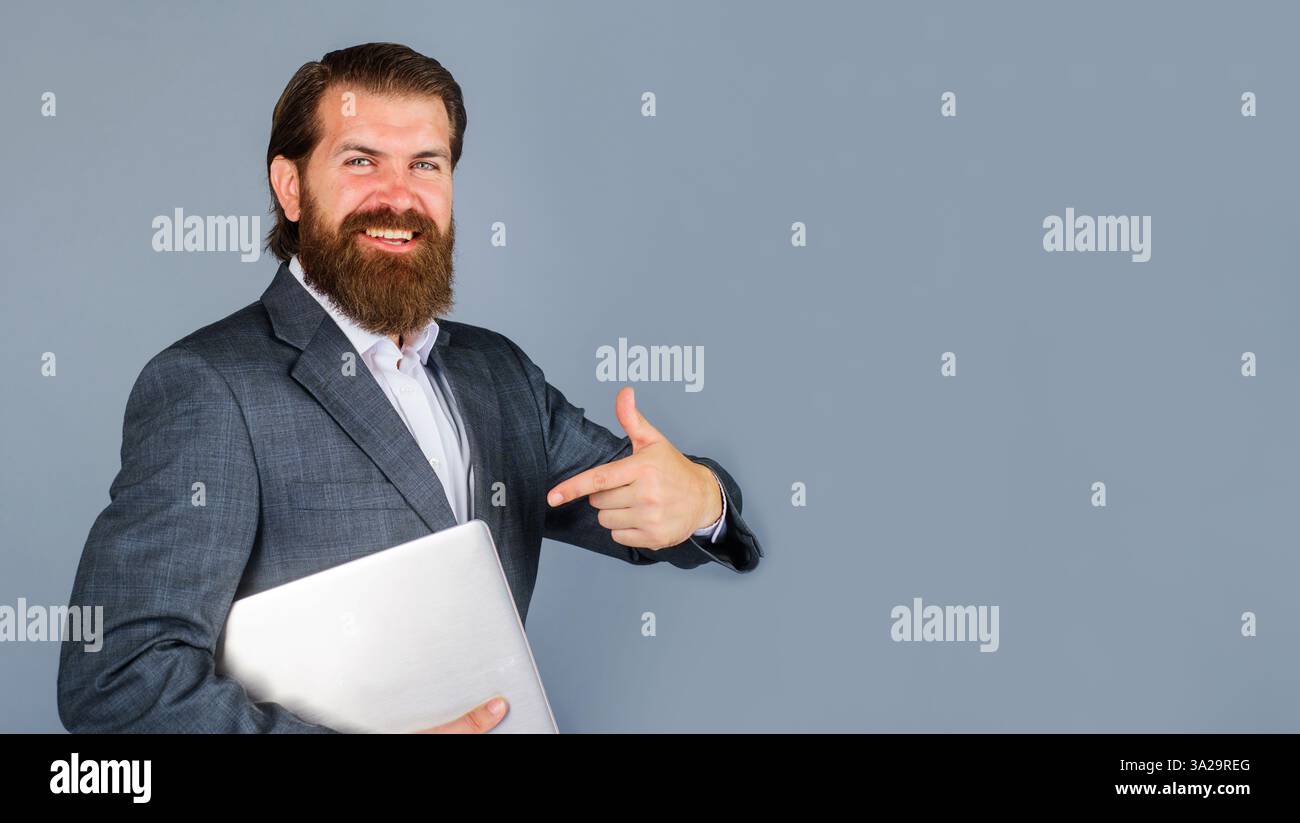 Uomo d'affari in abbigliamento formale che punta il dito sul laptop. Tecnologia moderna, Internet, comunicazione. Uomo barbuto con taccuino. Spazio di copia per il responsabile Foto Stock